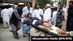 People carry a man who was injured in a suicide bomb attack at an election-campaign rally in eastern Afghanistan's Kama district on October 2.