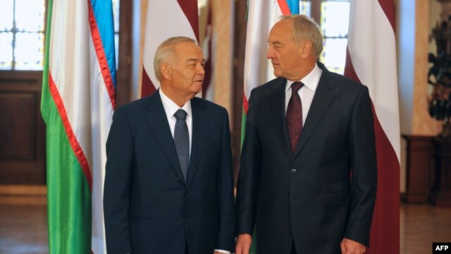Latvian President Andris Berzins (right) and Uzbek counterpart Islam Karimov pose in front of their national flags as they meet in Riga on October 17.