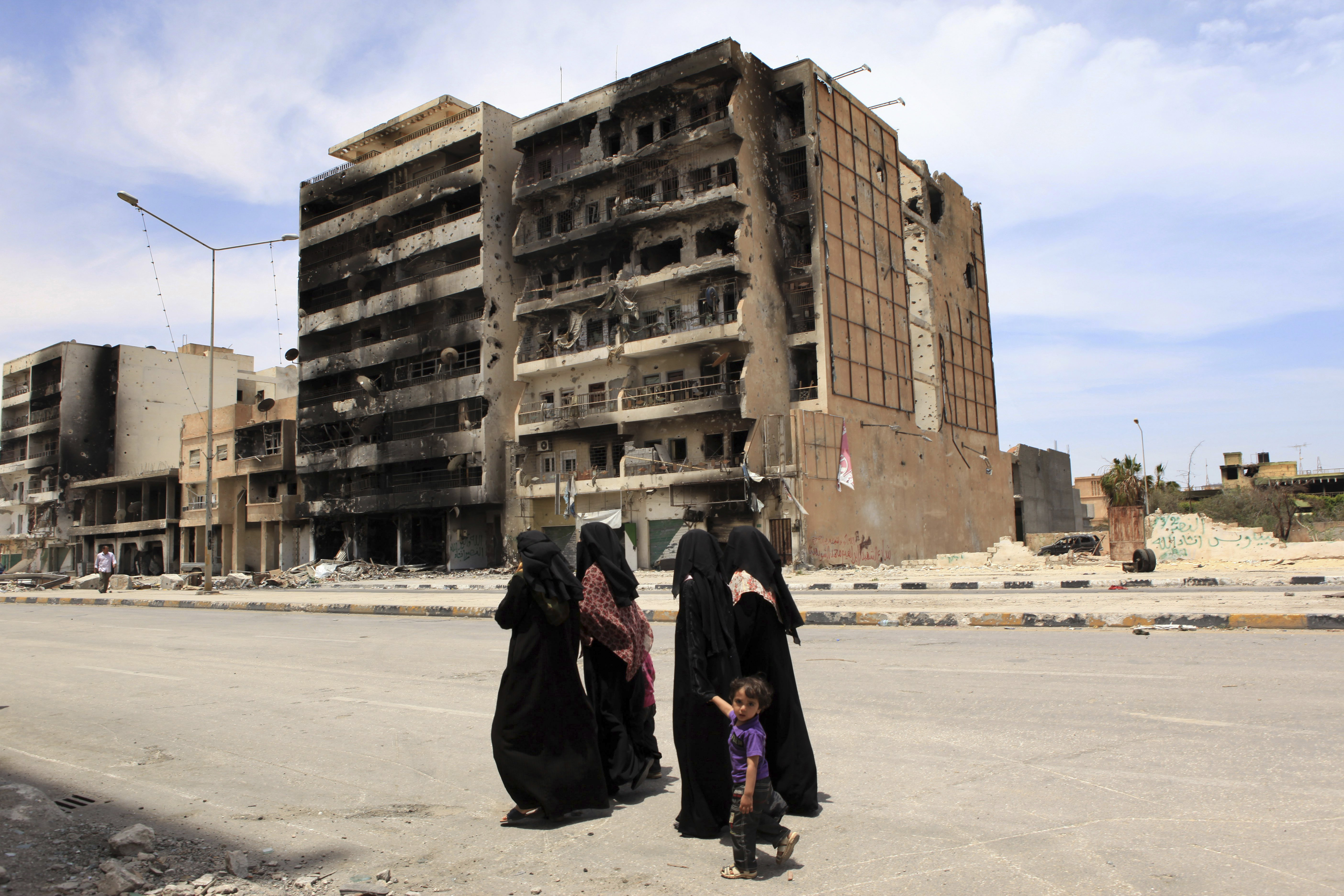 Women walking in front of bombed out buildings in Misrata