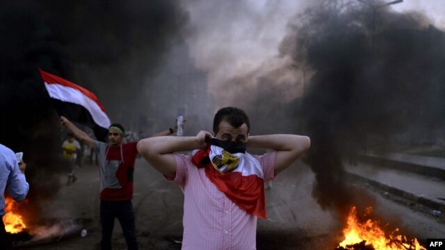 An Egyptian protestor covers his face with his national flag during clashes between supporters of Egypt's ousted President Muhammad Morsi and security forces in Cairo on August 30.