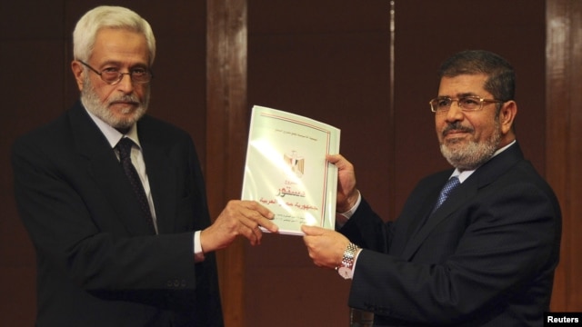 Constituent assembly chairman Hossam El-Gheriany gave President Muhammad Morsi (R) the final constitutional draft on December 1.