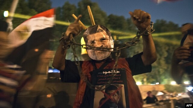 A man wearing a mask of ousted President Muhammad Morsi shows his handcuffed hands outside the presidential palace in Cairo on July 19, while Morsi opponents gather to mark the 40th anniversary of the Six-Day War against Israel.