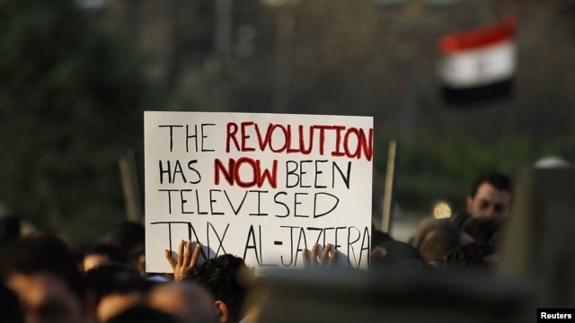 Egyptian antigovernment protesters carry a sign outside the Egyptian television center in Cairo during demonstrations that toppled the Mubarak regime in February 2011.