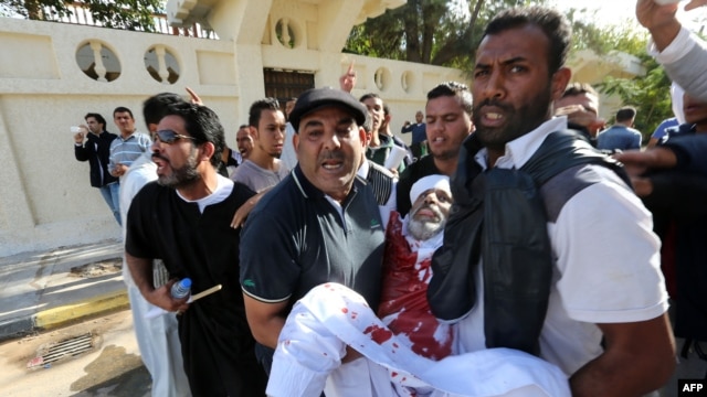 People assist a man who was injured after Libyan militiamen opened fire on a crowd wanting them to move out of their headquarters on November 15 in southern Tripoli.