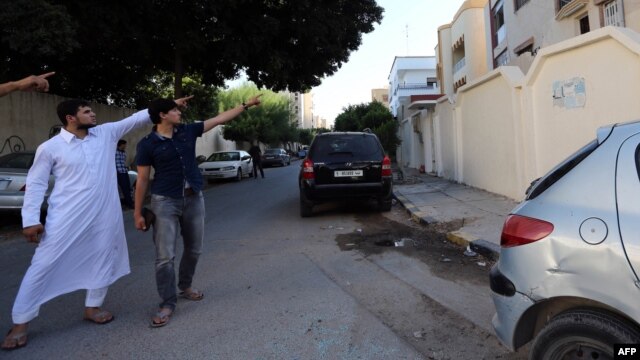Abdullah al-Raghie (left) and Abdul Moheman al-Raghie, the sons of Al-Qaeda suspect Abu Anas al-Libi, point at the house next to the scene where their father was seized by U.S. forces in a commando raid in Nofliene.