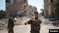 A Kurdish fighter from the People's Protection Units (YPG) gestures in Raqqa, Syria.