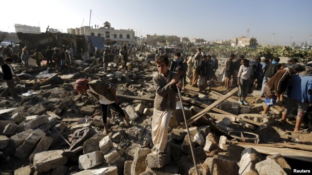 People gather at the site of an air strike in a residential area near Sanaa airport on March 26.