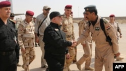 A handout picture released by the Iraqi premier's press office shows Prime Minister Haidar al-Abadi (center) shaking hands with army officers upon his arrival in Mosul on July 9.