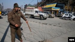 An Indian policeman lays barbed wire set up as a barricade outside the office of the United Nations Military Observer Group for India and Pakistan during restrictions in Srinagar, the summer capital of Indian Kashmir, on February 10.