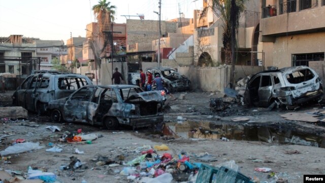 Residents walk through the site of a car bomb attack in eastern Baghdad.