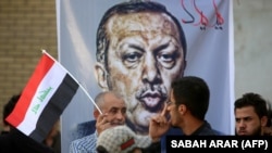 Iraqis stand in front of a banner mocking Turkish President Recep Tayyip Erdogan during a demonstration in Baghdad on October 8 to demand the withdrawal of Turkish troops from the Bashiqa camp in northern Iraq.