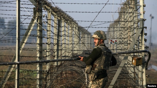 An Indian Border Security Force (BSF) soldier patrols near the fenced border with Pakistan in Jammu and Kashmir state.