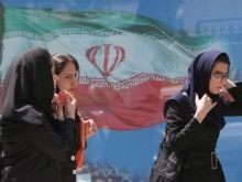 Iran - Iranian women pass a billboard of Iran's national flag at a street in Tehran, 23Apr2007
