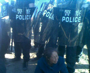 In a cellphone photo sent by an onlooker, a Mongolian lady sits in front of riot police, June 25, 2011.