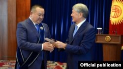Ex-President Almazbek Atambaev (right) bestows an award on adviser Ikramjan Ilmiyanov in November 2017.
