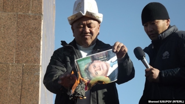 Former regional police chief Abdulla Kapparov burns a portrait of Kyrgyz President Almazbek Atambaev on Osh's central square.