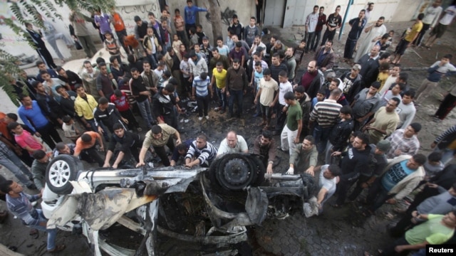 Palestinians gather around a destroyed car after what witnesses said was an Israeli air strike in Gaza City on November 20.