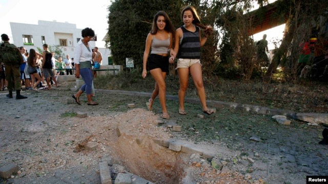 Onlookers walk past damage caused by a rocket fired from Lebanon into Israel near the northern city of Nahariya on August 22.