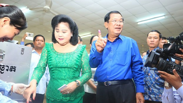 Prime Minister Hun Sen and his wife Bun Rany dip their fingers in indelible ink after casting their ballots at a polling station in Kandal province's Takhmao city, June 4, 2017.