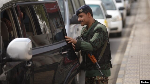 A Yemeni police trooper checks a car at a checkpoint on the road leading to Sanaa International Airport on August 6.
