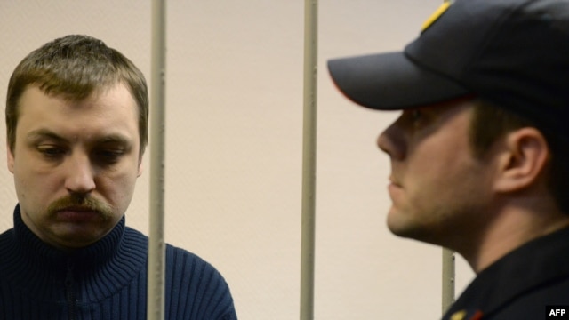 Mikhail Kosenko (left), one of the activists accused of violence at a rally on the eve of President Vladimir Putin's inauguration, stands in a defendant's cage in a court in Moscow in October 2013.