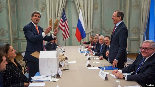 U.S. Secretary of State John Kerry (standing left) holds up a pair of Idaho potatoes as a gift for Russian Foreign Minister Sergei Lavrov (standing right) at the start of their meeting at the U.S. ambassador's residence in Paris on January 13.