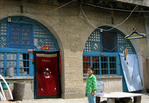 A Chinese girl stands outside her cave home in Yan'an, May 28, 2005.