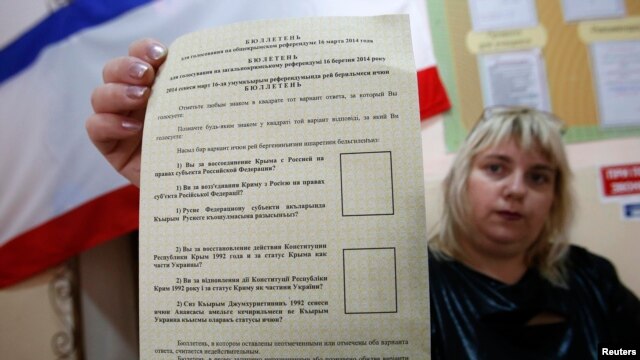 An election commission official shows a ballot paper for the referendum at a polling station in Simferopol on March 15.