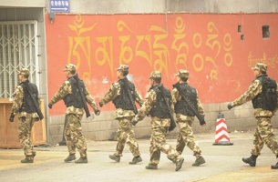 Armed Chinese PLA soldiers walk down a street with Tibetan writing on the wall in Chengdu in Sichuan province on Jan. 27, 2012.