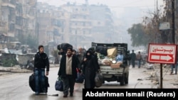 People carry their belongings as they flee deeper into the remaining rebel-held areas of Aleppo, Syria, on December 13.