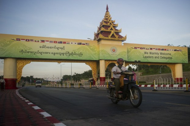 Commuters ride a motorcycle under a gate welcoming participants to the upcoming ASEAN Summit in Naypyidaw, Nov. 10, 2014.