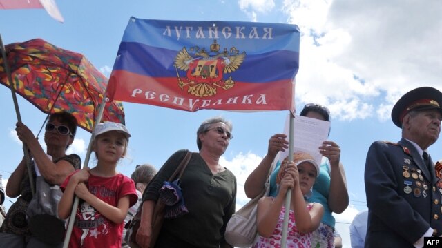 Children hold a flag of the self-styled 'People's Republic of Luhansk' during a rally in the eastern Ukrainian city of Luhansk in June.