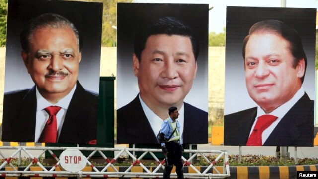 A policeman stands guard next to giant portraits of Pakistani President Mamnoon Hussain, Chinese President Xi Jinping, and Pakistani Prime Minister Nawaz Sharif ahead of Xi's visit to Islamabad.