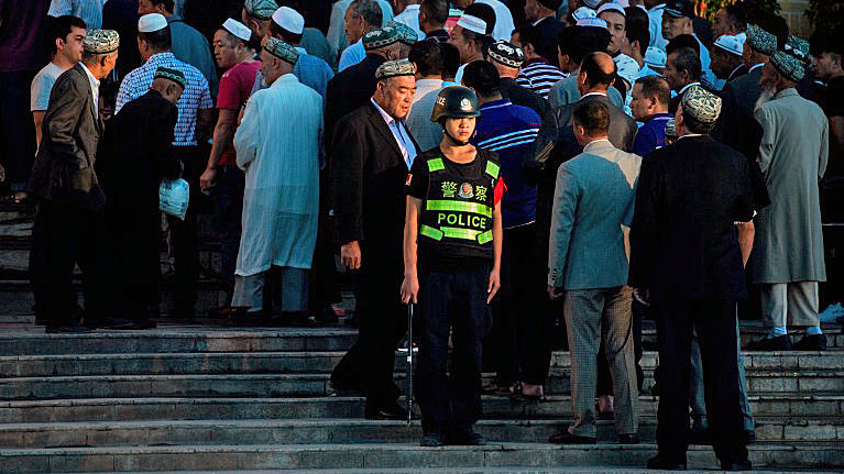 A Chinese policeman stands guard as Muslims arrive for the Eid al-Fitr morning prayer at the Id Kah Mosque in Kashgar, northwestern China's Xinjiang Uyghur Autonomous Region, June 26, 2017.
