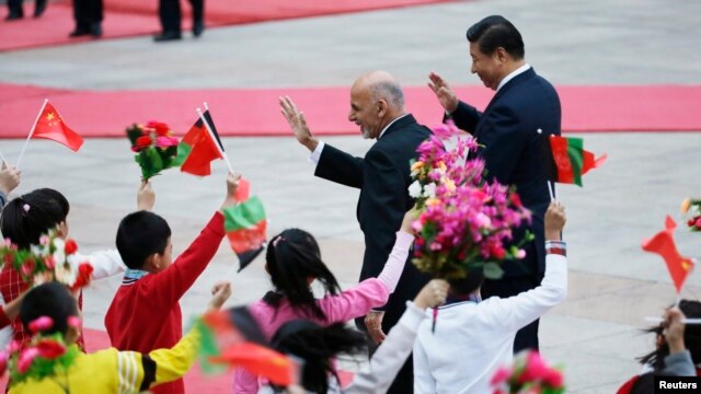Afghan President Ashraf Ghani (left) and China's President Xi Jinping wave to students during a welcoming ceremony outside the Great Hall of the People, in Beijing on October 28.