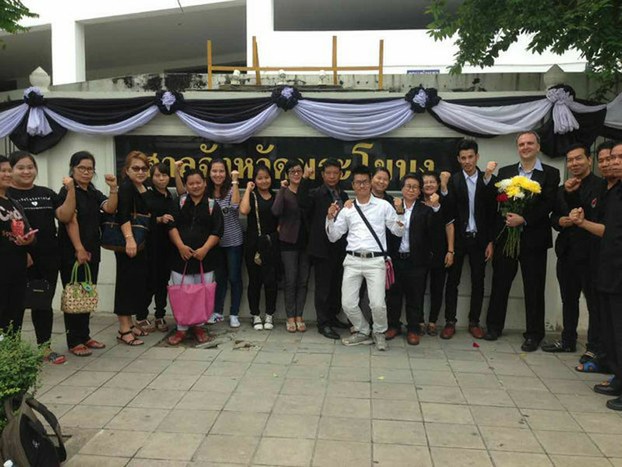 Andy Hall, holding a bouquet of flowers, is joined by supporters and workers from Myanmar at the Supreme Court in Bangkok, Nov. 3, 2016.