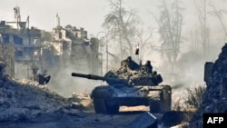Syrian pro-government forces drive a tank through a newly retaken district of Aleppo's Old City on December 8.