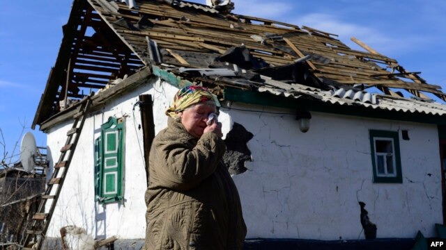 An elderly woman wipes away tears as she stands in front of a damaged house in Nikishyne, southeast of Debaltseve, in the conflict zone in eastern Ukraine on March 11.