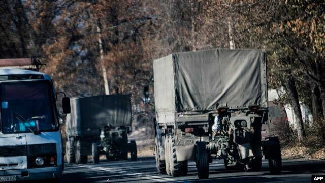 Trucks without license plates tow a 122mm howitzer artillery piece through Makiivka on November 9.