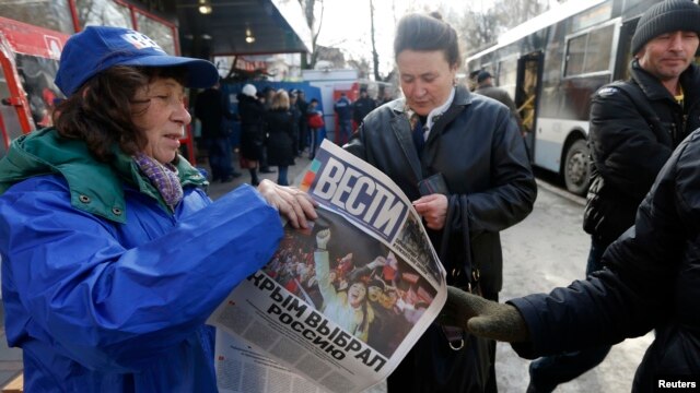 A woman hands out free newspapers with the headline 'Crimea Chooses Russia' on a street in Simferopol on March 17.