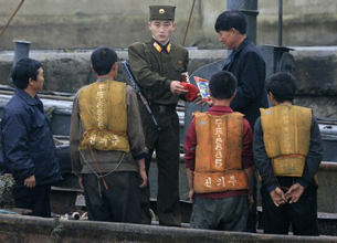 A North Korean border guard checks the documents of boat passengers in Sinuiju, Oct. 25, 2006.