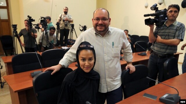 Iranian-American correspondent Jason Rezaian and his Iranian wife, Yeganeh Salehi, pose while covering a press conference at Iran's Foreign Ministry in Tehran in September 2013.