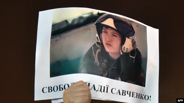 A demonstrator in Kyiv holds aloft a picture of the Ukrainian army officer captured by pro-Russian insurgents and taken to Russia, Nadia Savchenko, with the words 'Free Nadia Savchenko.'