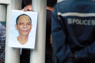 A demonstrator holds a poster of deceased dissident Li Wangyang through barricades at a protest in Hong Kong, June 30, 2012.