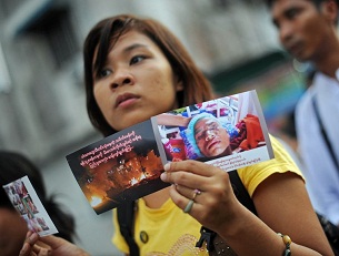 A woman holds a photo of an injured monk at a protest in Rangoon, Dec. 2, 2012.