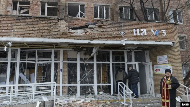 A priest stands in front of a hospital destroyed after shelling between Ukrainian forces and pro-Russian separatists in the eastern city of Donetsk on January 19.