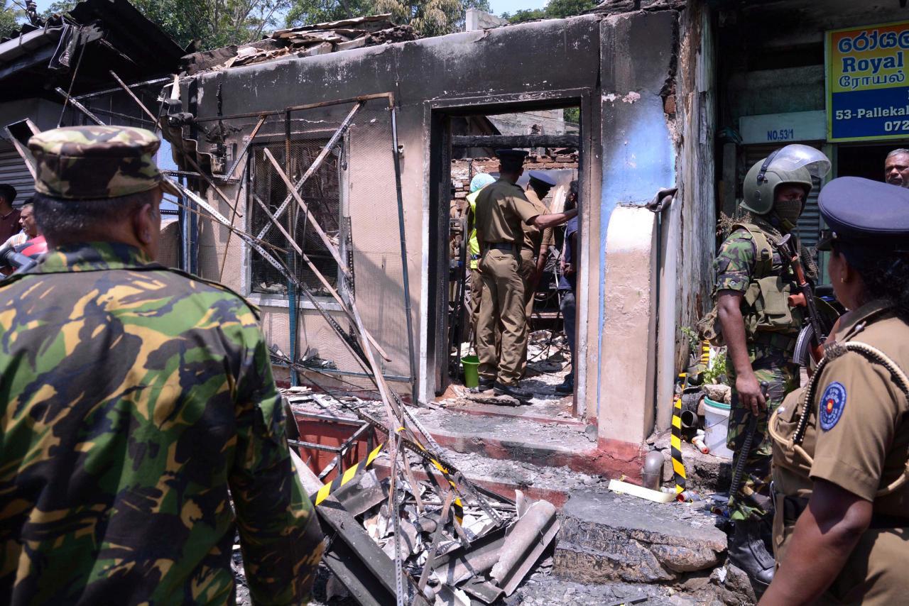 Sri Lanka's Special Task Force and Police officers stand guard near a burnt house after a clash between two communities in Digana, central district of Kandy, March 6, 2018.