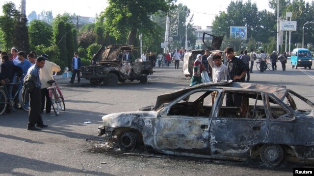 Residents pass burnt-out cars after the unrest in the eastern Uzbek town of Andijon on May 13, 2005.