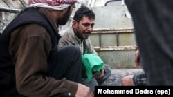 Bashar al-Toum (center) cries as he holds the body of one of his three dead children in a car on the way to the cemetery in the Syrian city of Douma. At least 13 were killed, including six children, due to bombing in the rebel-held city.