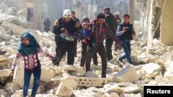 People and a civil-defense worker carry children at a damaged site after an air strike on rebel-held Idlib on March 19.
